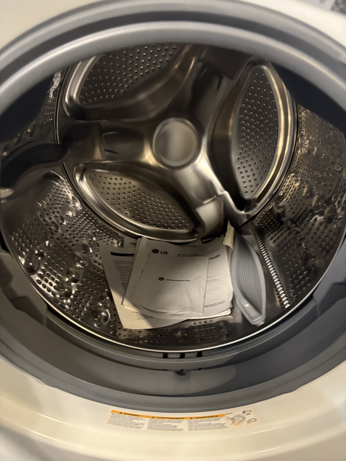 Inside the stainless steel LG washer drum with the owner's manuals