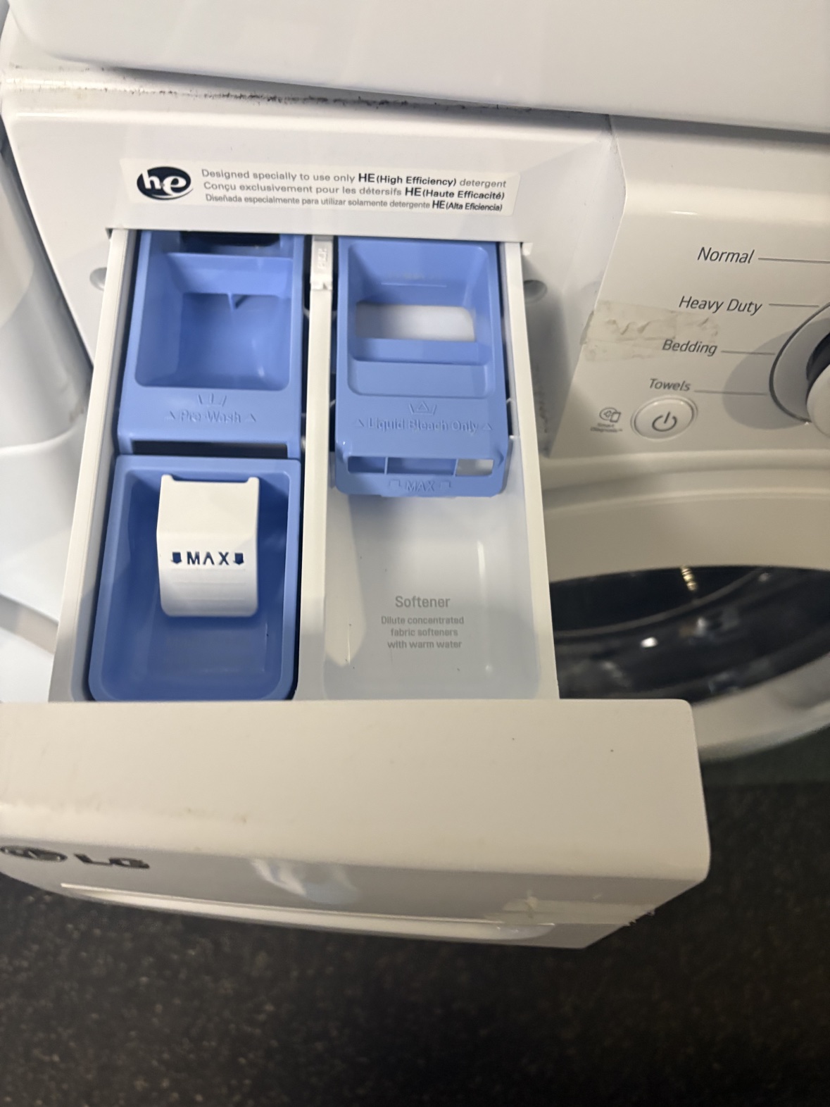 LG washer detergent dispenser drawer open, showing the pre-wash, bleach and softener compartments